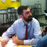 man wearing tie at table holding pen