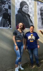 two women posing with large portrait